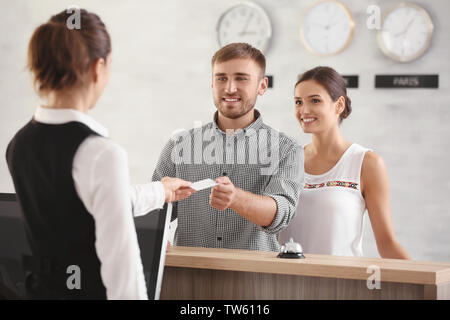 Jeune couple recevant carte clé de chambre d'hôtel à la réception Banque D'Images