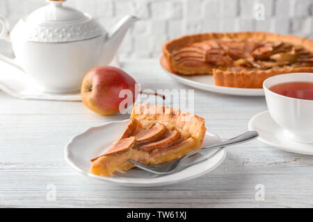 Plaque avec morceau de tarte aux poires savoureuses sur table en bois blanc Banque D'Images