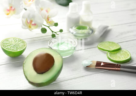 Composition avec masque cosmétique, d'avocat et de tranches de lime sur fond de bois Banque D'Images