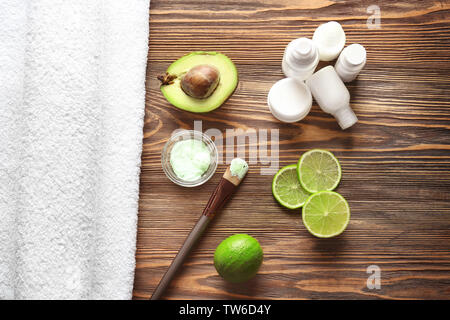 Composition avec masque cosmétique, d'avocat et de tranches de lime sur fond de bois Banque D'Images