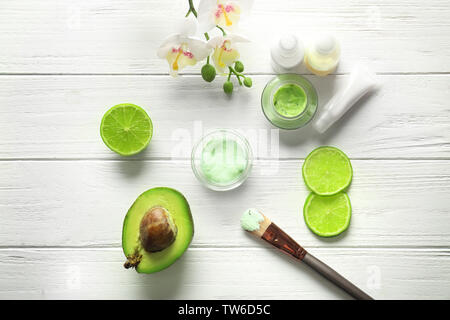 Composition avec masque cosmétique, d'avocat et de tranches de lime sur fond de bois Banque D'Images