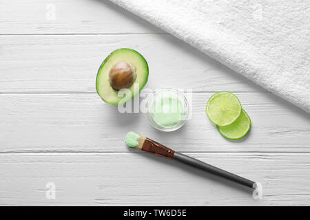 Composition avec masque cosmétique, d'avocat et de tranches de lime sur fond de bois Banque D'Images