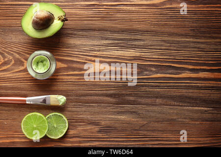 Composition avec masque cosmétique, d'avocat et de tranches de lime sur fond de bois Banque D'Images