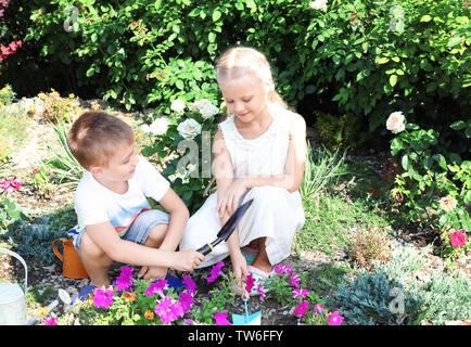 Cute little children planter des fleurs dans le jardin Banque D'Images