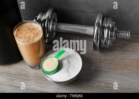 La composition avec Protein Shake, poudre et haltère sur table Banque D'Images