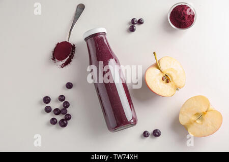 La composition avec l'açaï jus en bouteille de verre sur fond clair Banque D'Images