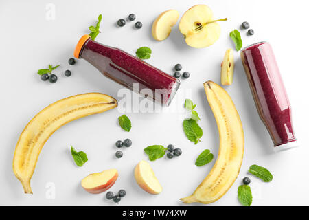 La composition avec l'açaï jus dans des bouteilles en verre sur fond clair Banque D'Images
