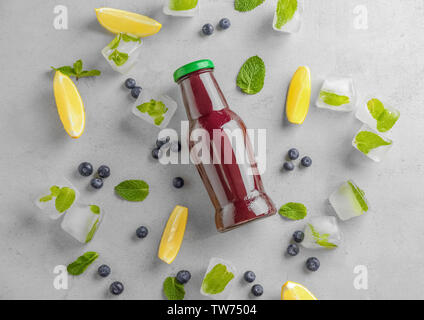 La composition avec l'açaï jus en bouteille de verre sur fond clair Banque D'Images