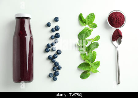 La composition avec l'açaï jus en bouteille de verre sur fond clair Banque D'Images