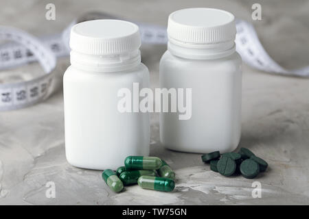 Les contenants avec des capsules et des comprimés de spiruline sur table Banque D'Images