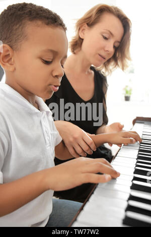 Garçon afro-américain avec l'enseignant Apprendre à jouer du piano à l'intérieur Banque D'Images