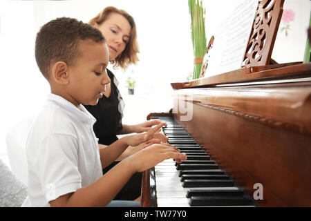 Garçon afro-américain avec l'enseignant Apprendre à jouer du piano à l'intérieur Banque D'Images