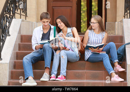 Les jeunes étudiants qui étudient en étant assis sur des escaliers à l'extérieur Banque D'Images