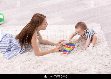 Jeune mère et mignon bébé jouant sur le plancher à la maison Banque D'Images