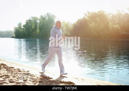 Homme mûr en marche près de la rivière Banque D'Images