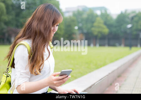 Belle femme asiatique studen using mobile phone in campus Banque D'Images