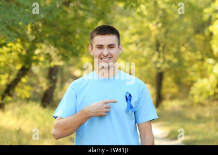 Jeune homme pointant sur ruban bleu sur son t-shirt à l'extérieur. Concept de la sensibilisation au cancer de la prostate Banque D'Images