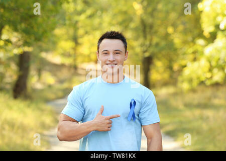 Jeune homme pointant sur ruban bleu sur son t-shirt à l'extérieur. Concept de la sensibilisation au cancer de la prostate Banque D'Images