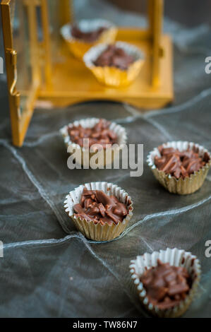 En Amandes enrobées de chocolat en papier doré avec golden phare en arrière-plan. Banque D'Images