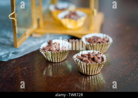 En Amandes enrobées de chocolat en papier doré avec golden phare en arrière-plan. Banque D'Images