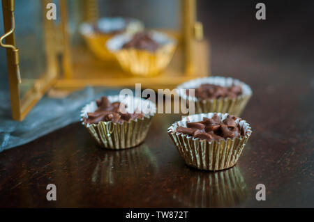 En Amandes enrobées de chocolat en papier doré avec golden phare en arrière-plan. Banque D'Images