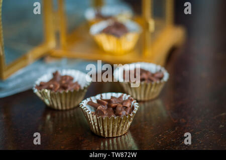 En Amandes enrobées de chocolat en papier doré avec golden phare en arrière-plan. Banque D'Images