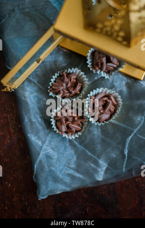 En Amandes enrobées de chocolat en papier doré avec golden phare en arrière-plan. Banque D'Images