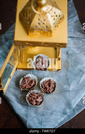 En Amandes enrobées de chocolat en papier doré avec golden phare en arrière-plan. Banque D'Images