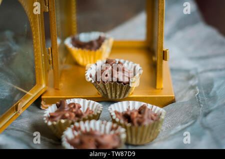 En Amandes enrobées de chocolat en papier doré avec golden phare en arrière-plan. Banque D'Images