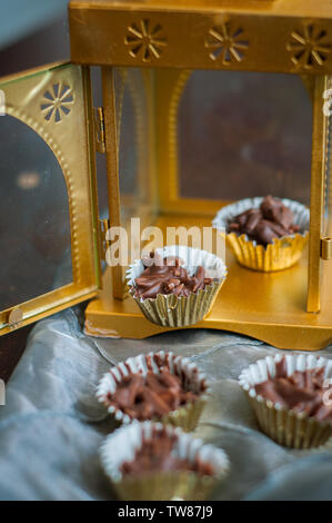 En Amandes enrobées de chocolat en papier doré avec golden phare en arrière-plan. Banque D'Images