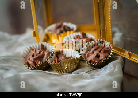 En Amandes enrobées de chocolat en papier doré avec golden phare en arrière-plan. Banque D'Images