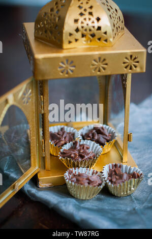 En Amandes enrobées de chocolat en papier doré avec golden phare en arrière-plan. Banque D'Images