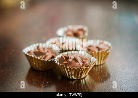 En Amandes enrobées de chocolat en papier doré sur un fond de bois. Banque D'Images