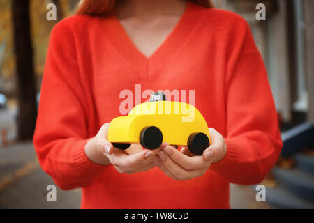 Woman holding toy jaune taxi cab, à l'extérieur Banque D'Images