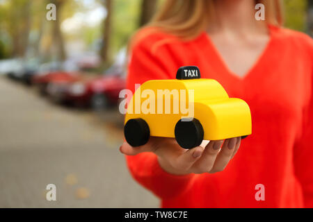 Woman holding toy jaune taxi cab, à l'extérieur Banque D'Images