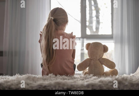 Petite fille aux ours assis sur le plancher dans la chambre. Concept de l'autisme Banque D'Images