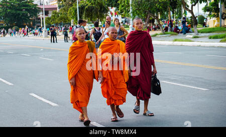 Phnom Penh, Cambodge - Août 2016 : jeunes moines en robe orange distinctive en marchant dans la rue en face d'un groupe de touristes. Banque D'Images