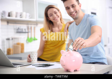 Jeune couple avec tirelire à la maison Banque D'Images