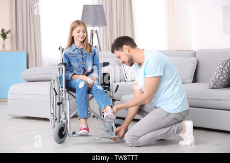 Jeune homme prendre soin de l'adolescente en fauteuil roulant à l'intérieur Banque D'Images