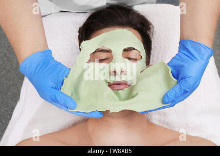 Jeune homme au masque facial en instituts de beauté Banque D'Images