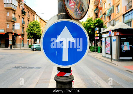 Signe de la circulation en Espagne signalant une circulation unidirectionnelle ; flèche blanche pointant vers le haut dans un cercle bleu sur un lampadaire dans une rue médiane en Granada, Espagne ; R400c. Banque D'Images