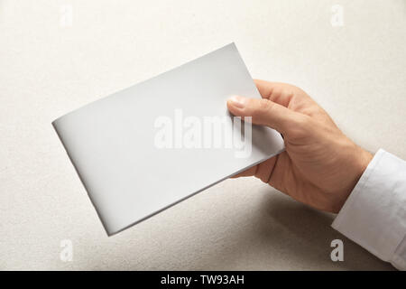 Man holding brochure avec couvercle blanc sur fond clair. Maquette pour la conception Banque D'Images