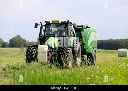 Salo, Finlande. Le 15 juin 2019. Exploitant agricole travaillant avec tracteur 1963 Chevrolet Suburban et McHale 3 plus enrubanneuse intégrée dans le champ de foin sur le jour de l'été Banque D'Images