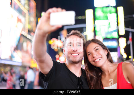 Dating jeune couple heureux en amour en prenant l'auto-portrait photo selfies sur Times Square, New York City at night. Beaux jeunes touristes s'amuser ce jour, Manhattan, USA. Asian Woman, man Banque D'Images