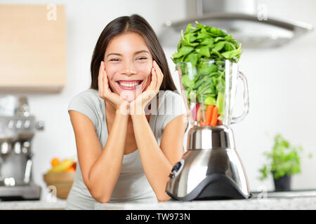 Smoothie vert femme faisant des smoothies de légumes avec le mélangeur. Concept de vie saine alimentation portrait de belle jeune femme la préparation de boisson avec des épinards, carottes, céleri etc à la cuisine.