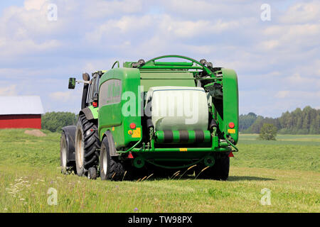 Salo, Finlande. Le 15 juin 2019. Tracteur Deutz-Fahr et McHale 3 plus l'ensilage en balles en plastique vert feuille dans champ de foin sur une journée ensoleillée d'été. Banque D'Images