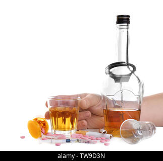 L'homme menotté holding verre d'alcool près de différents médicaments sur fond blanc Banque D'Images