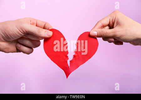Coeur de papier se déchire en deux la moitié sur un fond de couleur, gros plan. Problèmes de rapport Banque D'Images