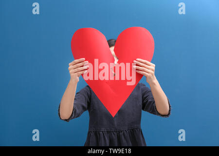 Jeune femme dans la moitié du coeur de papier se déchire sur un fond de couleur. Problèmes de rapport Banque D'Images