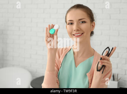 Femme tenant un contenant de plastique avec des lentilles de contact et de lunettes, à l'intérieur Banque D'Images